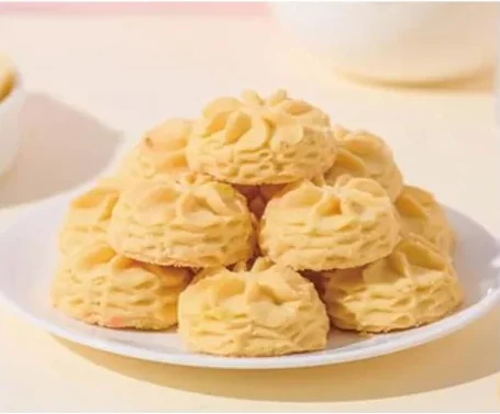 Freshly baked Little Blossom butter cookies stacked on a white plate